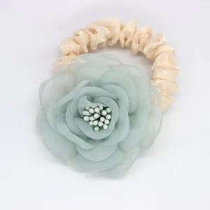 Détail du chouchou fleur en organza vert clair avec élastique en tissu plissé beige crème