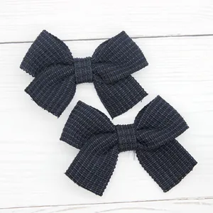 Detail of dark blue tweed bow hair clips with elegant textured weave and fringe