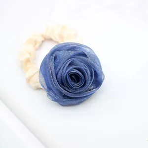 Detail of a large blue mesh rose hair tie with creamy white satin fabric texture