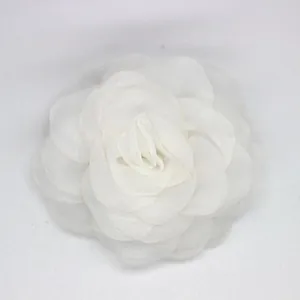 Detalle de elegante broche de camelia en organza blanca con pétalos de tela multicapa