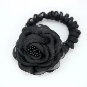 Chouchou élégant avec rose en tissu noir multicouche et perles sur fond blanc pur