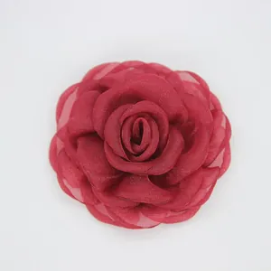Detalle de broche de camelia de organza rojo oscuro con delicadas capas de tela
