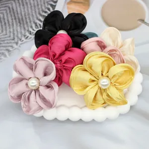 Détail de chouchous fleurs en satin avec perles centrales en couleurs élégantes