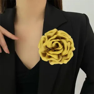 Close-up of a large yellow 3D satin rose brooch pinned on a black suit lapel