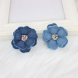 Detailed view of handmade denim fabric flowers in dark and light blue with beaded centers