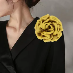 Detailed view of a bright yellow large satin flower brooch on a black suit lapel