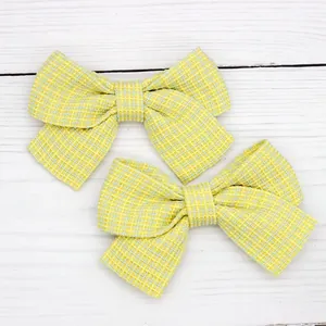 Pair of yellow plaid bow hair clips for girls on a white wooden background