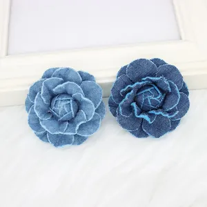 Detailed view of layered denim camellia flowers in light and dark blue with frayed edges