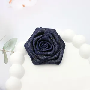 Dettaglio di una rosa in tessuto blu scuro fatta a mano con fili dorati su un vassoio