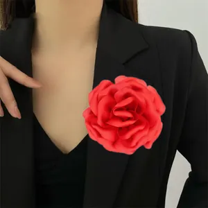 Detail of a large red fabric rose brooch pinned on a black suit lapel for elegant styling