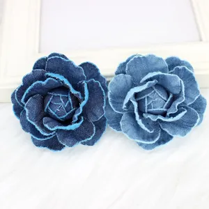 Detail of two handmade denim camellia flower brooches with frayed edges in blue tones