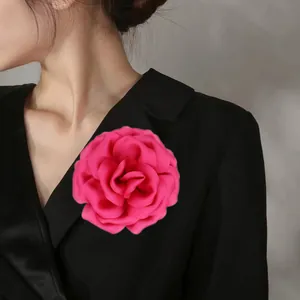 Detailed view of large rose pink fabric brooch pinned on a black suit lapel
