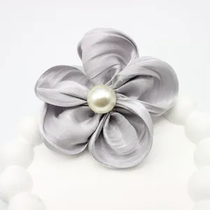 Détail d'une fleur en satin argenté avec perle centrale et texture de soie brillante