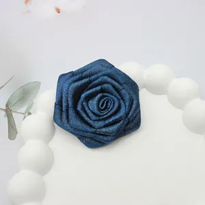 Dettaglio di rosa in nastro blu scuro fatta a mano con fili d'oro su vassoio bianco