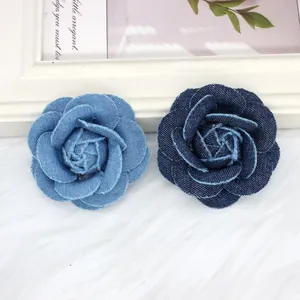 Close-up of handmade denim camellia flowers with frayed edges in light and dark blue denim