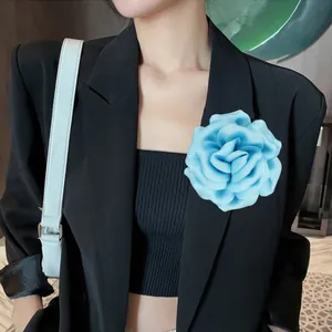 Detail of light blue satin rose brooch pinned on a black professional suit blazer
