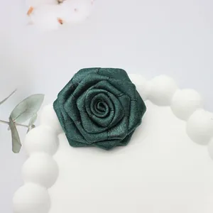 Dettaglio di un fiore di rosa in tessuto verde scuro fatto a mano con trama satinata