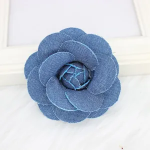 Close-up of deep blue denim camellia flower with layered petals and visible stitching