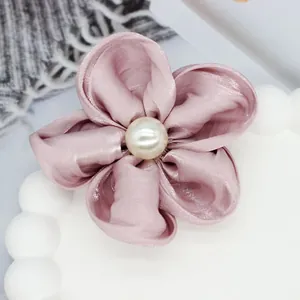 Détail de la pince à cheveux fleur en satin rose avec perle élégante au centre