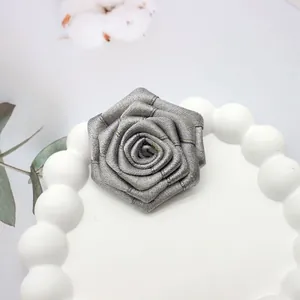 Dettaglio di una rosa in tessuto grigio argento fatta a mano con fili d'oro e petali