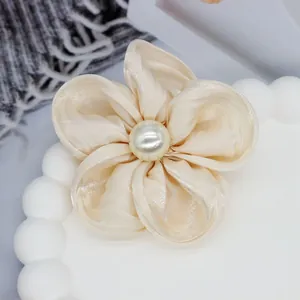 Vue macro d'un accessoire floral en organza crème avec détail de perle centrale