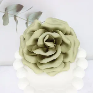 Detailed close-up of a handmade 10cm olive green satin peony flower on a white wavy pedestal