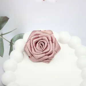 Dettaglio della rosa in nastro rosa fatta a mano con trama in filo dorato per accessori
