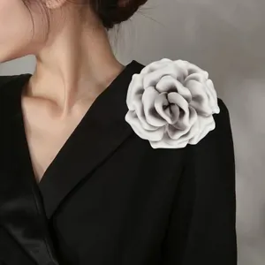 Close-up of elegant grey satin fabric rose brooch pinned on a black V-neck suit jacket