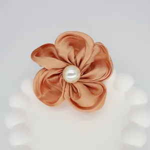 Détail d'un accessoire fleur en satin champagne fait main avec une perle centrale