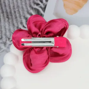 Vue détaillée d'une barrette fleur en satin fuchsia avec pince crocodile en métal
