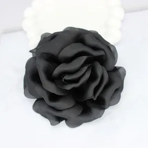 Detailed view of a handmade black satin rose flower accessory on marble background