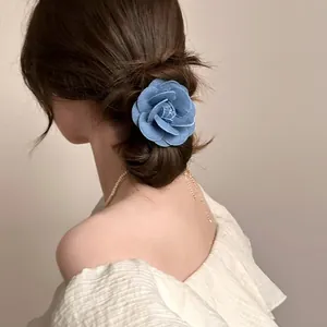 Close-up of blue denim camellia flower hair tie worn on an elegant low bun