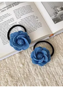 Detailed view of blue denim camellia flower hair ties on a vintage book background