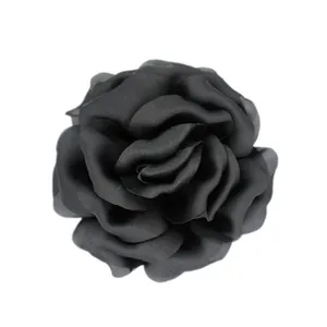Close-up of elegant black satin fabric rose flower brooch with detailed 3D petals