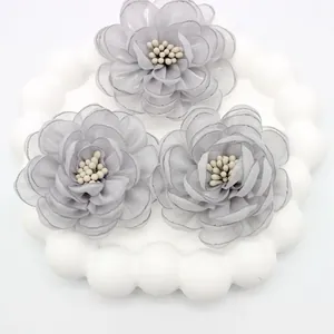Detailed view of handmade grey organza fabric camellia flowers with pearl stamen center