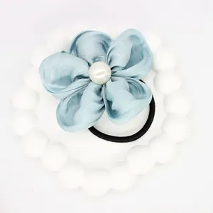 Detail of light blue fabric flower hair tie with central pearl and black elastic band