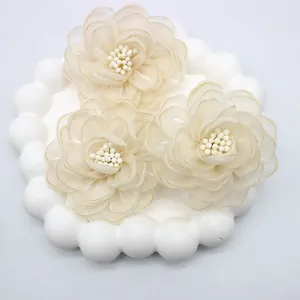 Macro shot of three cream-colored organza camellia flowers with delicate beaded centers