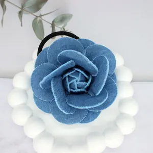 Elegant denim blue camellia flower hair scrunchie on a white decorative ceramic plate