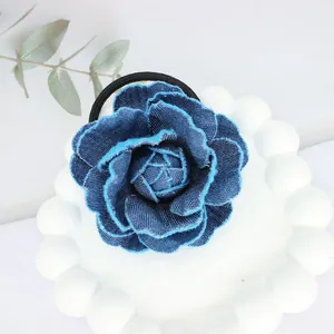 Elegant denim blue camellia flower hair scrunchie with layered fabric petals and elastic band
