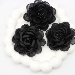 Detailed view of three black organza camellia fabric flowers with beaded centers