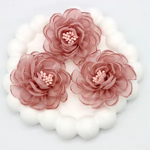 Detailed macro view of 3D pink organza camellia fabric flowers with beaded center