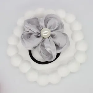 Detailed close-up of a silver floral hair scrunchie with a central white pearl detail
