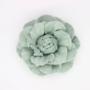 Macro detail of handmade sage green fabric camellia flower with layered felt petals
