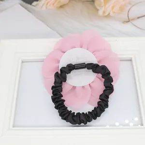 Dettaglio dei petali di rosa in chiffon rosa e dell'elastico per capelli nero sul retro