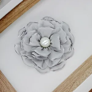 Macro view of handmade grey satin flower brooch with singed edges and central pearl