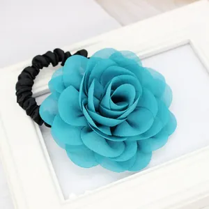 Dettaglio dell'elastico per capelli con fiore in chiffon azzurro su cornice bianca