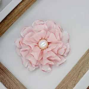 Detail of pink satin peony flower with soft petals and a white pearl center brooch
