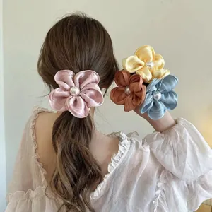 Elegant satin flower hair scrunchie with large pearl accent for stylish ponytail updos