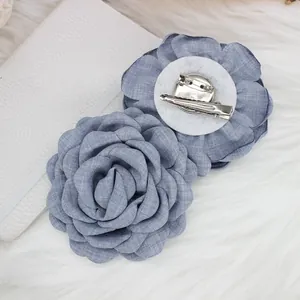Detailed back view showing the metal duckbill clip and safety pin on blue fabric rose