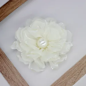 Detail of multi-layered cream fabric peony brooch with pearl center and satin texture